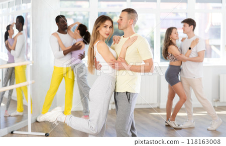 Young adult couple dancing playful bachata during group class Young adult couple dancing playful bachata during group class 118163008
