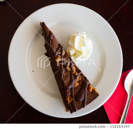 Slice of chocolate sponge cake with whipped cream and walnuts Slice of chocolate sponge cake with whipped cream and walnuts 118163147