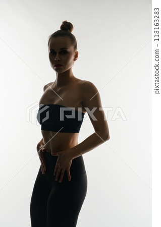 Fit woman's silhouette posing against a bright backdrop Fit woman's silhouette posing against a bright backdrop 118163283