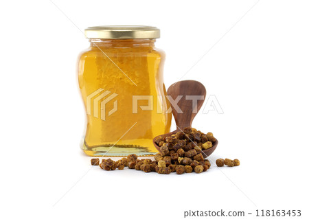 Jar of golden honey with a wooden spoon of bee bread isolated on a white background 118163453