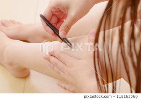 一位女士正在去除腿上多餘的毛髮 118163560