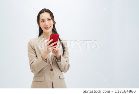 Smiling female business person using a smartphone 118164960