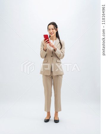 Full-body photo of a female business person using a smartphone 118164961