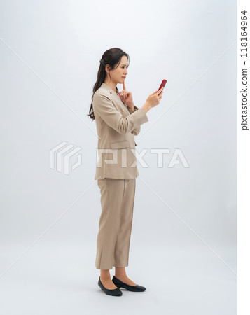 Full-body photo of a female business person worried while looking at her smartphone Full-body photo of a female business person worried while looking at her smartphone 118164964