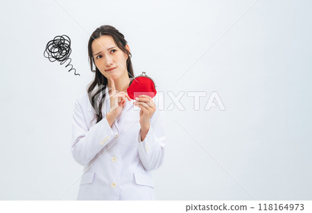 A woman in a white coat holding a wallet and worrying 118164973