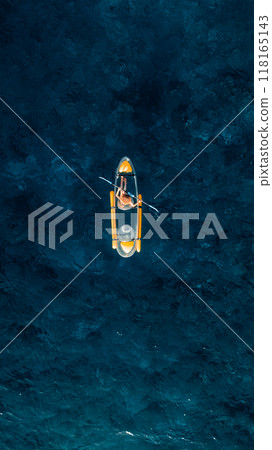 Vertical shot: Woman on kayak in tropical blue ocean. Drone view, top down 118165143