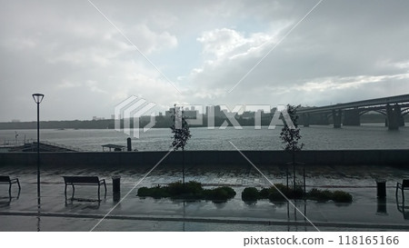 Cityscape view with a long bridge over a wide river under a cloudy sky in the distance 118165166