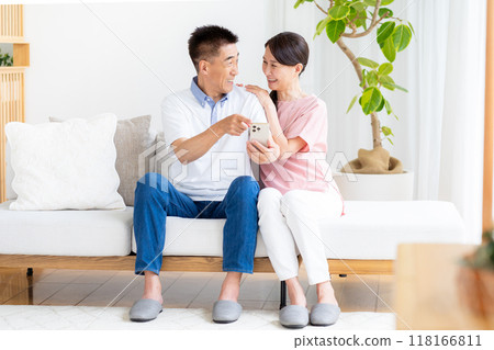 Senior couple looking at a smartphone in the living room 118166811
