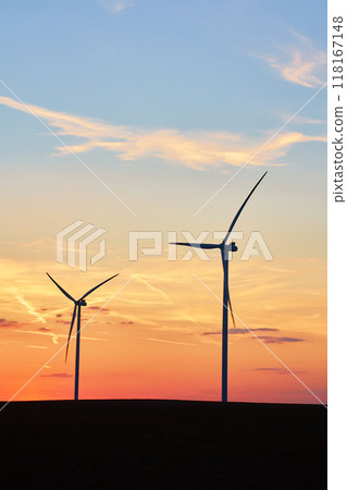 Silhouetted wind turbines in countryside landscape during sunset. Wind power plant generating clean energy. Concept of renewable and sustainable energy 118167148