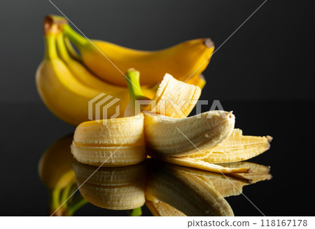 Ripe juicy bananas on a black reflective background. 118167178