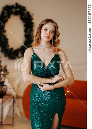 A woman in a green dress poses against the backdrop of a Christmas interior. A woman in a green dress poses against the backdrop of a Christmas interior. 118167378