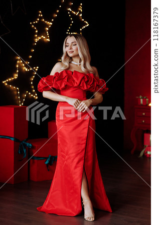 A woman in a red dress stands in front of a Christmas tree. Full length. A woman in a red dress stands in front of a Christmas tree. Full length. 118167379
