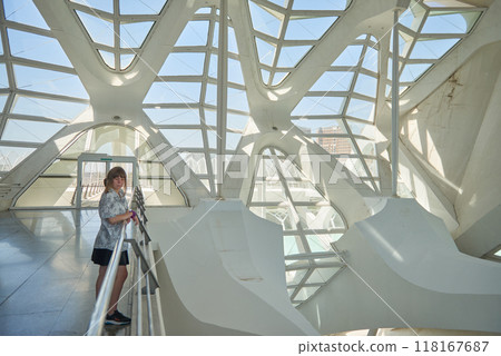 Young Woman Exploring the Architectural Splendor of Valencia's Science Museum in the City of Arts and Sciences Complex. Immersive Science Experience: Girl Engages with Interactive Exhibits Inside 118167687