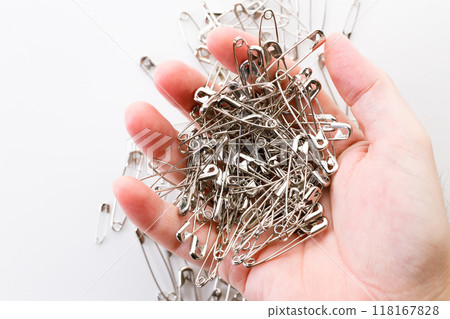 Hand holding safety pins. 118167828