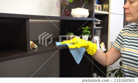 Young Woman Dusting in Living Room with Yellow Gloves - Housekeeping and Apartment Cleaning Young Woman Dusting in Living Room with Yellow Gloves - Housekeeping and Apartment Cleaning 118168563