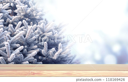 Christmas background. Blank wooden table top on sunny winter forest backdrop. Wood terrace flooring and branch of pine covered with frost. Holiday xmas banner with branches of fir tree. Copy space 118169426