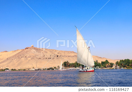 Traditional sailing boat felucca, Nile river near Aswan, Egypt. A famous tourist attraction - sailing boat ride 118169427