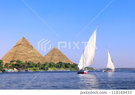 Famous Great Pyramids of Chephren and Cheops and traditional sailing boat felucca, Nile river, Egypt. A famous tourist attraction - sailing boat ride Famous Great Pyramids of Chephren and Cheops and traditional sailing boat felucca, Nile river, Egypt. A famous tourist attraction - sailing boat ride 118169433