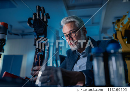 Robotics engineer adjusting, calibring robotic prosthetic hand. Concept of modern technology in medicine. Robotic prosthetics, biomechatronics and neuroscience. Robotics engineer adjusting, calibring robotic prosthetic hand. Concept of modern technology in medicine. Robotic prosthetics, biomechatronics and neuroscience. 118169503