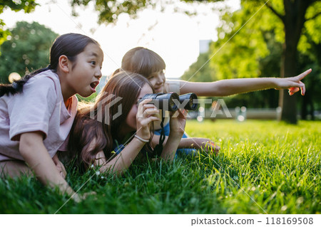 Young girl students learning about nature and wildlife in urban environment, using binoculars and observing animals in public park. 118169508