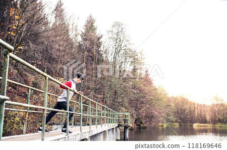 Sporty man preparing for run, stretching in park by lake. Morning workout for young man. Sporty man preparing for run, stretching in park by lake. Morning workout for young man. 118169646