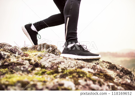 Close up of runner's legs, feet with running shoes durig off-road jog in nature on dirt running trail. 118169652