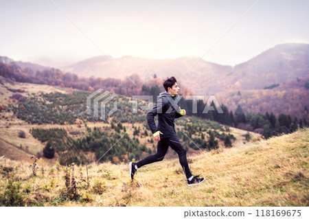 Male runner jogging in nature on dirt running trail. Morning running training for young man. Male runner jogging in nature on dirt running trail. Morning running training for young man. 118169675
