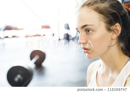 Young fitness girl with sweat on face feeling exhausted after hard workout in gym. Young fitness girl with sweat on face feeling exhausted after hard workout in gym. 118169747