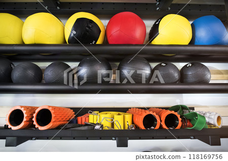 Rows of gym equipment, rubber medicine balls on racks for strength training in gym. 118169756