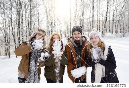 Group of friends on a walk in the snowy nature, holding snowballs . First snowfall of the season. 118169773