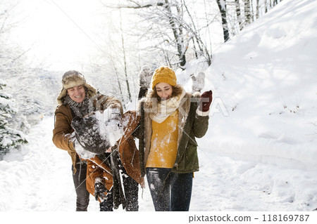 Friends in snowball fight in snowy nature. First snowfall of the season. 118169787