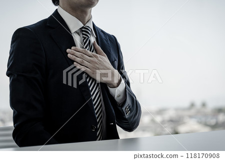 Male businessman in a suit holding his hand on his chest (monochrome, black and white) Male businessman in a suit holding his hand on his chest (monochrome, black and white) 118170908