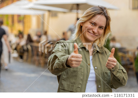 Happy girl showing thumbs up like gesture positive something good positive feedback on city street 118171331
