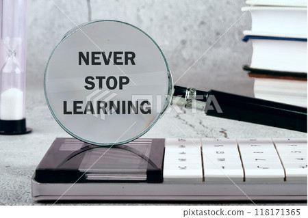 Never stop learning written on the background through a magnifying gla 118171365