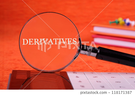 Derivatives word written through a magnifying glass standing vertically on a calculator on an orange background, front view 118171387