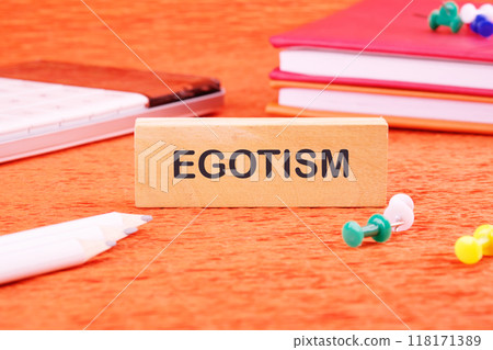 Concept image. the word EGOTISM on a wooden bar in front of an orange background, front view 118171389