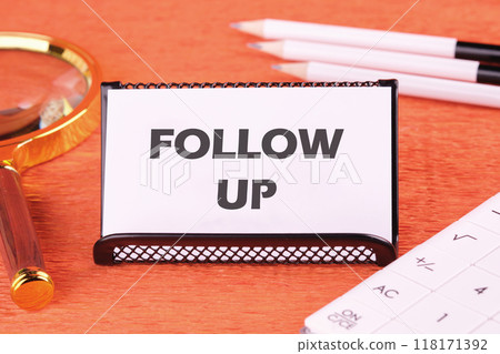Business concept. Copy space. The words Follow Up on a white business card, close-up in front of an orange background, front view Business concept. Copy space. The words Follow Up on a white business card, close-up in front of an orange background, front view 118171392