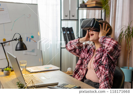 Business woman using virtual reality online VR app headset to simulation 3D at home office workplace Business woman using virtual reality online VR app headset to simulation 3D at home office workplace 118171668