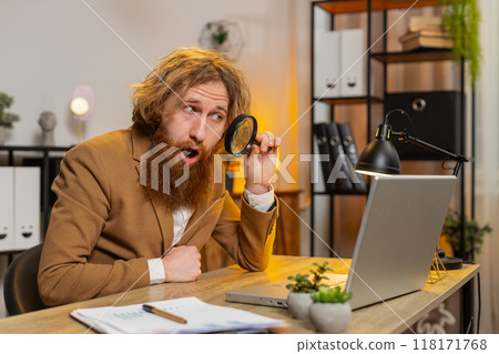 Business man working at home office holding magnifying glass looking at laptop screen wow expression 118171768