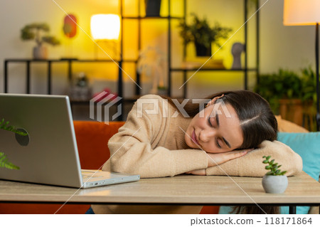Bored sleepy business woman worker works on laptop leaning on hands falling asleep at home table Bored sleepy business woman worker works on laptop leaning on hands falling asleep at home table 118171864