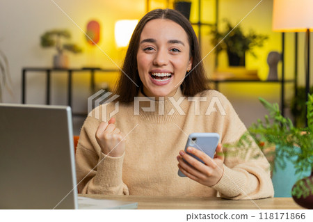 Caucasian woman at home table use smartphone celebrating success victory winning play online game 118171866