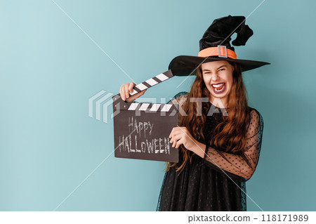 girl in Halloween witch costume on blue wall background girl in Halloween witch costume on blue wall background 118171989
