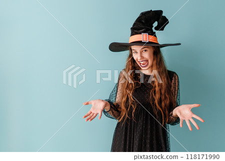 girl in Halloween witch costume on blue wall background girl in Halloween witch costume on blue wall background 118171990