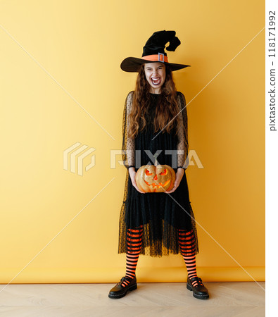 girl in witch costume with Halloween pumpkin girl in witch costume with Halloween pumpkin 118171992