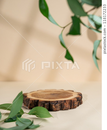 Abstract empty wooden cutting board with shadows and green leaves on a beige background.  118172233