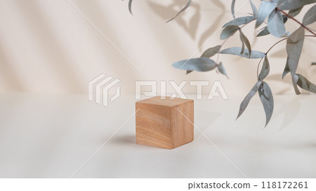 Abstract empty wooden cube with shadows and leaves on a beige background.  118172261