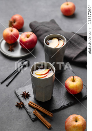 Homemade apple punch or cider with apples and cinnamon in gray cups on a dark background Homemade apple punch or cider with apples and cinnamon in gray cups on a dark background 118172604