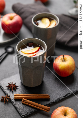 Homemade apple punch or cider with apples and cinnamon in gray cups on a dark background Homemade apple punch or cider with apples and cinnamon in gray cups on a dark background 118172608