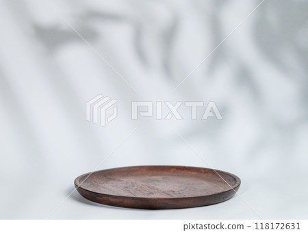 Abstract empty wooden plate with shadows leaves on a gray background. Abstract empty wooden plate with shadows leaves on a gray background. 118172631