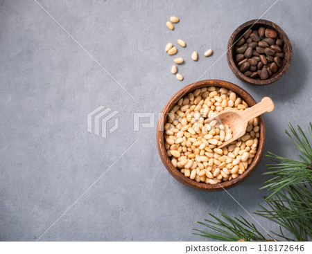 Pine nuts in a bowl on a blue background with branches of pine needles. Pine nuts in a bowl on a blue background with branches of pine needles. 118172646